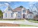 Elegant two-story home featuring a manicured lawn, arched windows, and a charming balcony at 7015 Polo Dr, Cumming, GA 30040