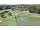 An aerial view of the golf course pond and clubhouse with sand traps and putting greens at 7015 Polo Dr, Cumming, GA 30040