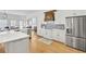 Open-concept kitchen with white cabinetry, stainless steel appliances, and a view into an adjacent living area at 7015 Polo Dr, Cumming, GA 30040