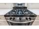 Close-up view of a stainless steel gas range with black accents and white subway tile backsplash at 312 Overview Dr, Canton, GA 30114