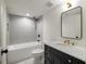 Elegant bathroom featuring a black vanity with marble countertop, gold fixtures, and a tiled tub and shower at 1563 Westwood Sw Ave, Atlanta, GA 30310