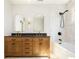 Modern bathroom features dual sinks, a wood vanity, a soaking tub with black fixtures, and bright, natural lighting at 1563 Westwood Sw Ave, Atlanta, GA 30310