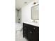 Stylish bathroom featuring a black vanity, marble countertop, gold fixtures, and tiled tub and shower at 1563 Westwood Sw Ave, Atlanta, GA 30310