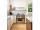 Stainless steel stove, white cabinets, farmhouse sink, wooden floors, and marble countertops create a functional kitchen space at 1563 Westwood Sw Ave, Atlanta, GA 30310