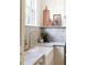 Close up of a white farmhouse sink with brass faucet, marble countertops and backsplash, and a wood shelf at 1563 Westwood Sw Ave, Atlanta, GA 30310