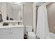 Well-lit bathroom with a white vanity, toilet, and a shower with neutral tile and white curtain at 201 Beacon Cv, Canton, GA 30114