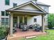 Cozy covered patio with brick flooring, outdoor seating, grill, and charming string lights at 201 Beacon Cv, Canton, GA 30114