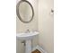 Bathroom features a pedestal sink with a round mirror and a decorative towel rack at 2349 Harshaw Ave, Lawrenceville, GA 30043