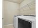The laundry room is equipped with modern, front load, white washer and dryer and a wire shelf at 2349 Harshaw Ave, Lawrenceville, GA 30043
