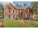 Elegant brick home featuring manicured landscaping, symmetrical design, and a welcoming entrance at 1558 Amberwood Creek Nw Dr, Kennesaw, GA 30152