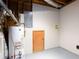 Utility area in the basement featuring a water heater, electrical panel, and storage space at 5199 Mainstreet Park Dr, Stone Mountain, GA 30088