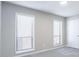 Bedroom featuring neutral walls, two bright windows, and soft gray carpet at 5199 Mainstreet Park Dr, Stone Mountain, GA 30088