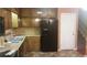 Kitchen featuring wood cabinets, black appliances, stainless steel sink, and access to the stairway at 7356 Caribou Trl, Riverdale, GA 30296