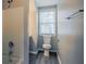 This is a bright bathroom featuring gray plank flooring, a shower and tub combination, and a toilet by the window at 5589 Claridge Cir, Lithonia, GA 30038