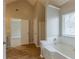 Bright bathroom featuring a soaking tub, vaulted ceilings and an adjoining doorway at 4060 Rockmill Cv, Ellenwood, GA 30294