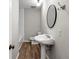 Bathroom with a pedestal sink, oval mirror and wooden floor at 67 Blue Springs Sw Ct, Lilburn, GA 30047