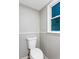 Powder room featuring wainscoting, a modern toilet, and a window for natural light at 67 Blue Springs Sw Ct, Lilburn, GA 30047
