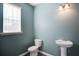 Cozy half-bathroom featuring a pedestal sink, modern fixtures, and natural light at 3480 Buffington Ln, Cumming, GA 30040