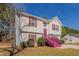 Side angled view of a charming home featuring red shutters, a vibrant pink staircase, and a well-kept lawn at 3420 Lineview Dr, Ellenwood, GA 30294