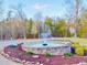 An opulent stone fountain is surrounded by a beautiful flower bed with a lush wooded landscape in the background at 2150 Fincher Rd, Canton, GA 30114