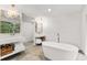 Spa bathroom with soaking tub, dual vanities, gold fixtures, and stone tile flooring at 150 Melody Ln, Fayetteville, GA 30215