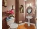 Charming powder room with decorative sink, round mirror, wood floors, pink flowers, and a toilet at 1043 Sugar Pike Way, Canton, GA 30115