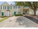 Inviting two-story townhouse with green shutters and door, complemented by a mature tree and well-maintained lawn at 112 Timber Mist Ln, Lawrenceville, GA 30045