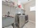 Modern laundry room featuring a gray utility sink, newer model washer and dryer and overhead shelving at 1591 Alder Se Ct, Atlanta, GA 30317