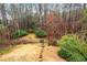 Secluded backyard with a stone path leading to a wooden fence and gate, surrounded by mature trees and lush greenery at 2557 Sixes Rd, Canton, GA 30114