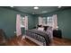 Green bedroom with a comfortable bed, hardwood floors, and natural lighting at 2569 Woodhill Ln, Atlanta, GA 30344