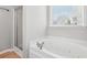 Bathroom featuring a modern tub with jets, a shower with glass door, and a window at 6491 Stonelake Sw Pl, Atlanta, GA 30331