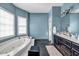 Bathroom with a bathtub, blue walls, black tile floors, a black cabinet, and a large mirror at 1450 Brandy Shoals Se Dr, Conyers, GA 30013