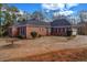 Back exterior of a red brick home featuring a two-car garage, surrounded by manicured bushes and a driveway at 1450 Brandy Shoals Se Dr, Conyers, GA 30013
