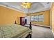 Main bedroom features carpet floors, yellow walls, ceiling fan, wardrobe, and a large window for natural light at 1450 Brandy Shoals Se Dr, Conyers, GA 30013