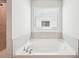 Close-up of white soaking tub with neutral tile accents and lots of natural light at 2025 Wyndham Pl, Conyers, GA 30013