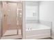 Bathroom with walk-in shower and soaking tub, neutral tiling, and natural light at 2025 Wyndham Pl, Conyers, GA 30013