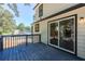 A view of the home's back deck featuring black railings, an outdoor light, and access to the home through a sliding glass door at 557 Old Friar Tuck Ln, Stone Mountain, GA 30087