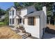 Beautiful two-story white home with black trim, stone accents, and lush greenery at 557 Old Friar Tuck Ln, Stone Mountain, GA 30087