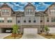 Townhome exterior featuring neutral siding, stone accents, individual garages, mature landscaping under a partly cloudy sky at 2020 Manor Pointe Dr, Cumming, GA 30041