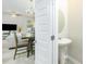 Bright bathroom featuring a pedestal sink and an oval mirror, complemented by an open-concept dining and living area in background at 375 Milton Dr, Covington, GA 30016