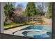 Relaxing pool area with a spa, lush greenery, stone accents, and a view of a private backyard oasis at 166 Erie Ave, Decatur, GA 30030