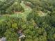 An aerial view of a lush golf course, surrounded by trees and a home nestled in a grove at 9570 Huntcliff Trce, Atlanta, GA 30350