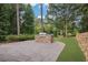 Outdoor kitchen on a patio with stone construction, built-in grill, and manicured backyard at 9570 Huntcliff Trce, Atlanta, GA 30350