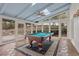Enclosed sunroom with a pool table, skylights, tile floor, and multiple windows offering serene views at 9570 Huntcliff Trce, Atlanta, GA 30350