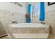 Bright bathroom featuring a corner tub with bright blue curtains at 684 Old Cumming Rd, Sugar Hill, GA 30518