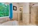 Bright bathroom featuring a corner tub and shower with neutral tile at 684 Old Cumming Rd, Sugar Hill, GA 30518