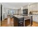 Open-concept kitchen with an island featuring a stovetop, stainless steel appliances and white cabinets at 684 Old Cumming Rd, Sugar Hill, GA 30518