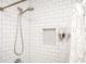 Close up of a shower with white subway tile, a shower niche, and a detachable shower head at 2411 Fair Ln, Decatur, GA 30032