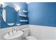 This bathroom features blue paint, shelving, oval mirror, white toilet, and modern fixtures at 3911 Ivy Ne Rd, Atlanta, GA 30342
