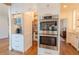 Hidden pantry and built in microwave and oven with white cabinetry and gold hardware at 3955 Graystone Preserve Pl, Cumming, GA 30040